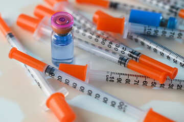 Close up of Pile of Single Use Syringes with Orange Safety Tips and Glass Vials
