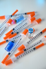 Close up of Pile of Single Use Syringes with Orange Safety Tips and Glass Vials