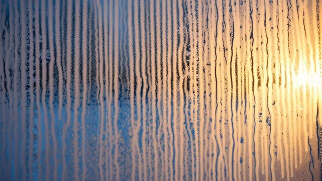 A closeup view of a dirty window with water droplets and streaks on it during sunset or sunrise with warm light, 4k video