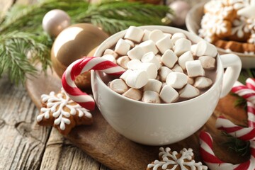 Tasty cocoa, marshmallows, candy canes, gingerbread cookies and Christmas decor on wooden table, closeup