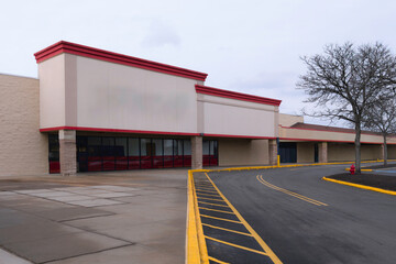Obraz premium A suburban American shopping mall stands closed, its empty building and deserted parking lot reflecting the passage of time and shifting landscapes of commerce and community.
