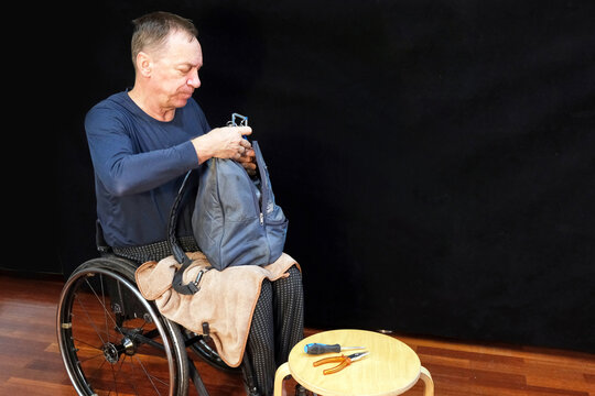 A man in a wheelchair holds a backpack in his hands