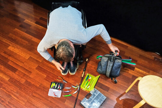 A man in a wheelchair removes a spinning reel from his backpack