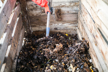 Turning Compost with a Garden Fork in a Wooden Compost Bin