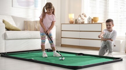 Cute little kids playing golf at home
