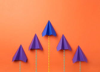 Obraz premium Paper planes with dotted lines as air route track on orange background
