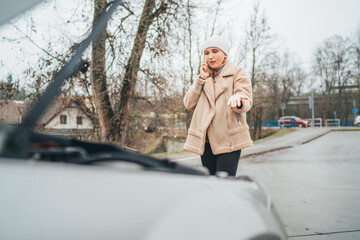 Car Motor failure on the road. Open bonnet point of view of middle aged woman calling service assistance using smartphone. Transportation, call service, and driver expirence concept image