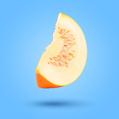 Piece of pumpkin in air on pale blue background. Gourd vegetable