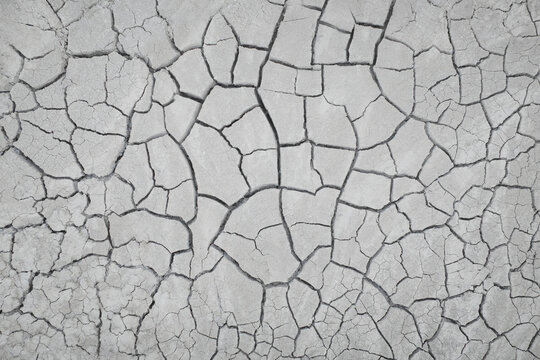 Aerial view of parched earth, a mosaic of cracks creating a stark, textured landscape under the intense sun, Centuripe, Sicilia, Italy.