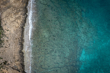 Vibrant coastal landscape showing the clear blue waters meeting the rocky shore at midday