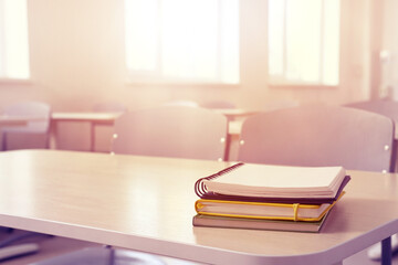 Notebooks on desk in sunlit school classroom