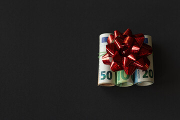 Money gift euros with decorative bow on black background
