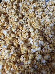 Caramel popcorn with glossy coating and golden texture, close-up view of sweet snack with crunchy surface and baked finish, warm tones and appealing contrast in natural light.