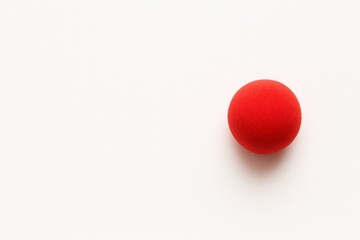 Soft red clown nose on a clean white minimal background