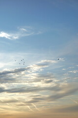 Fototapeta premium Sun lit ethereal white clouds on blue sky at sunset
