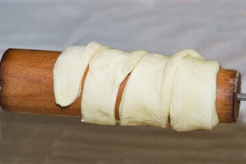 Mit Teigstreifen umwickelte Holzrolle - Backwerk Teig
