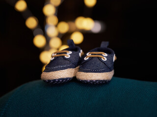 Blue baby shoes with warm lights in the background