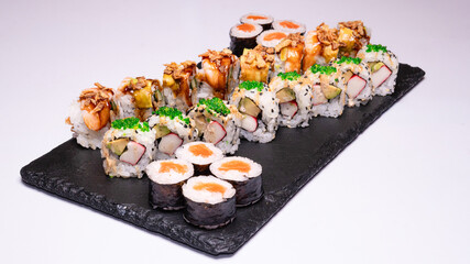 High-quality photo of an assorted sushi set arranged on a black slate serving board. photographed on a clean white background, ideal for use in restaurant menus, food blogs, Japanese cuisine promotion