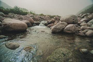 River flowing through rocks with a mountainous background.