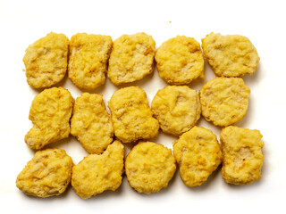 A pile of golden fried chicken nuggets on white background. The nuggets are golden brown and appear to be crispy. Fine popular poultry product.