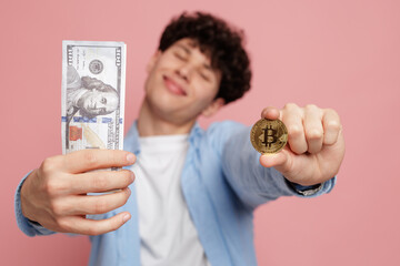 Young man holding cash and crypto coin on pink background cryptocurrency exchange concept