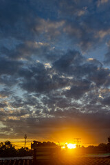 Fototapeta premium Sunset over the city with dramatic clouds and sunbeams.