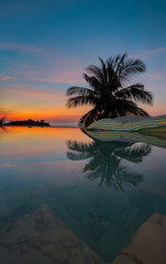 View from luxury villa at dusk, pool lighting, sun loungers for sunbathing, umbrellas from the sun, pillows for swimming in the pool, palm tree on background