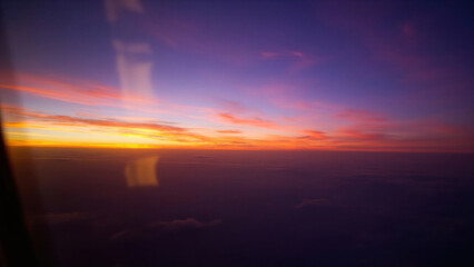 Vibrant sunset view from an airplane window with colorful sky and clouds