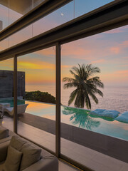 View from luxury villa at sunset, sun loungers for sunbathing, umbrellas from the sun, pillows for swimming in the pool, palm tree on background