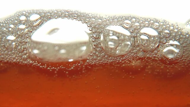 Macro texture of fermenting Tepache bubbles rising. Static abstract orange liquid background.