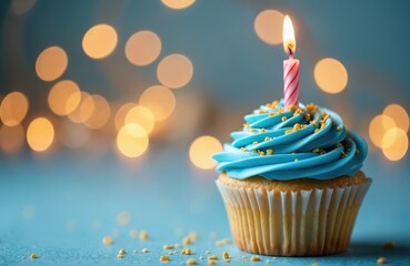 Blue frosted cupcake with candle and sprinkles sits on table. Soft bokeh lights in background create festive atmosphere for celebration, event, or party.