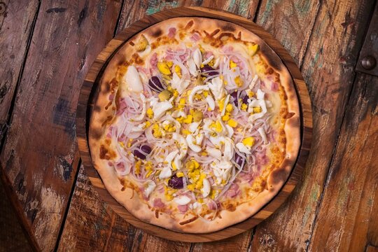 Pizza portuguesa de massa fina, com presunto, ovos, azeitona preta, cebola