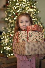 Little girl holding boxes with Christmas gifts,  Merry Christmas, winter holidays