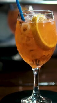 Glass of apperol spritz cocktail with orange slice on blue background. Closeup of summer drink, zoom in. High quality 4k footage