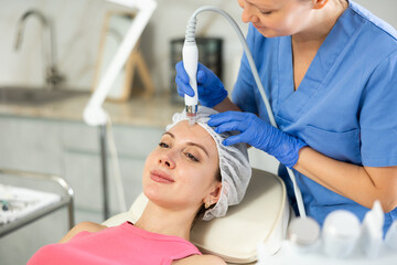 Female dermatologist performing cosmetology procedure for young girl, absorb blackheads and deeply clear skin and deep hydration for facial skin therapy in beauty clinic