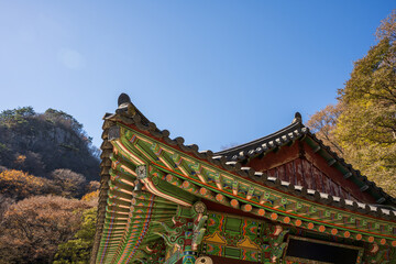 Naklejka premium Traditional Korean Temple Eaves with Colorful Dancheong Patterns Under Clear Autumn Sky