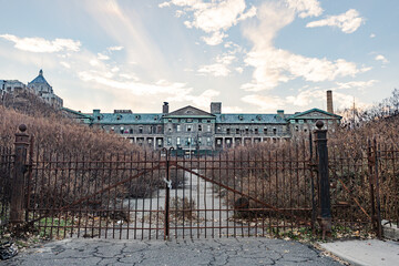 Abandoned institutional building behind rusty gate.