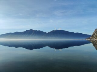 Misty Mountain Range Reflected in Calm Blue Lake at Dawn