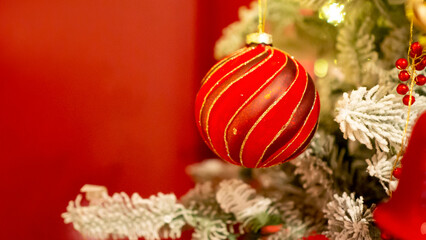 Red Christmas toys are hanging on the Christmas tree.