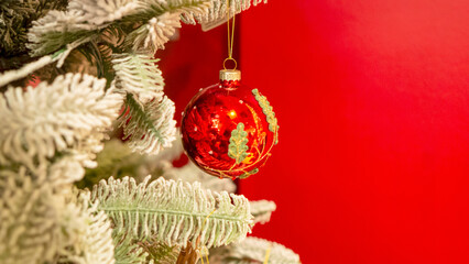 Red Christmas toys are hanging on the Christmas tree.