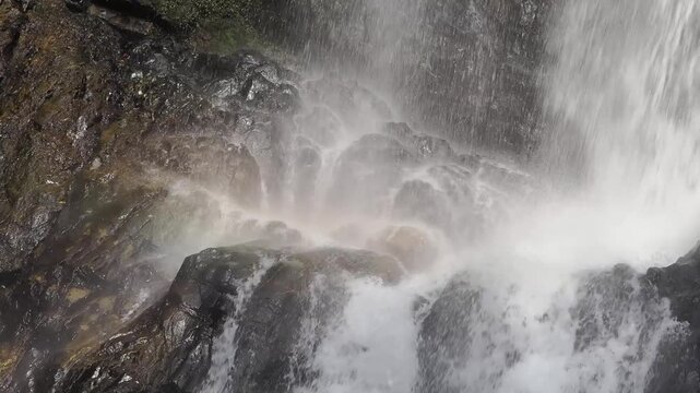 Waterfall is bathed in sunlight, creating a rainbow in the afternoon.