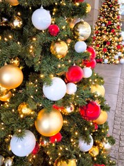 Two luxurious Christmas trees stand outside, decorated with red and gold baubles.