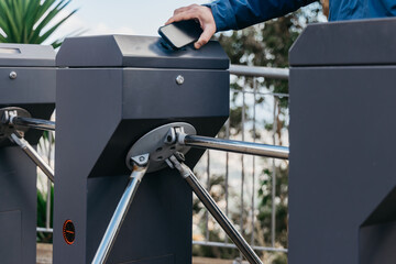 Individual using smartphone to access automated turnstile at a modern transit station, showcasing technology integration in urban transportation systems