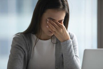 Screen time fatigue. Tired exhausted young female office employee overworked at computer feel discomfort rub eyes to relieve tension suffer from bad eyesight strain pain blurred vision at workplace