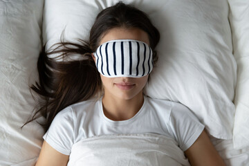 Quality night sleep. Peaceful tranquil young female sleeping in cozy bed under soft blanket with...