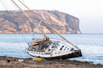 Javea Alicante 10 12 2025 – A stranded sailboat resting on the rocky coastline of Javea, Spain,...