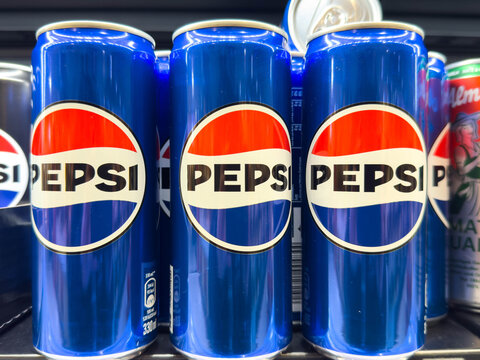 Villach, Austria - December 10, 2025: Pepsi soda cans are neatly arranged on a store shelf, showcasing vibrant blue packaging and iconic logo, representing popular beverage choice for refreshment