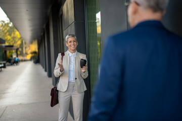 Businesswoman greeting colleague outside modern office building