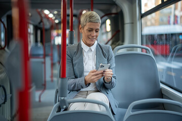 Businesswoman commuting on public transport using smartphone