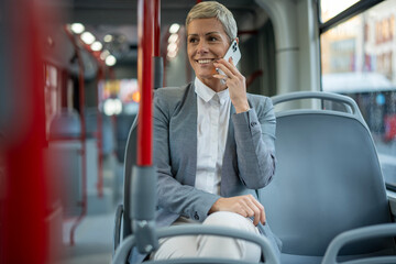 Businesswoman talking smartphone on bus commuting urban transport